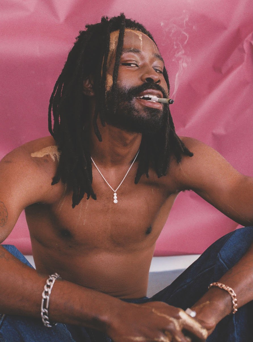 shirtless-man-sitting-on-ground-smoking-joint