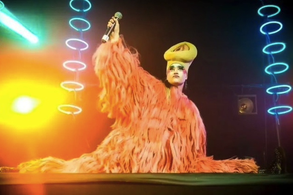 Peaches onstage in a furry orange body suit doing the splits