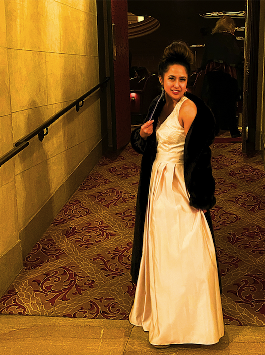 a Filipina femme in a long cream colored gown wearing a floor length black fur coar