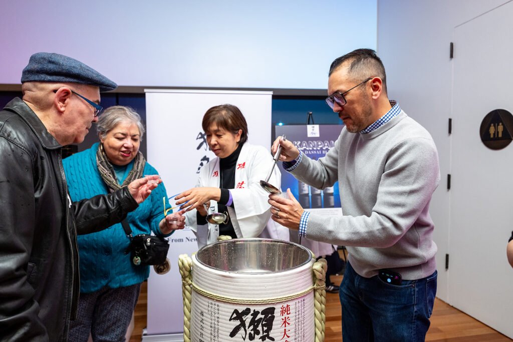 Guests sampling sake from a ceremonial barrel during Late Night Editions Art of Manga at the de Young Museum