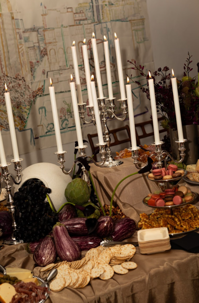 Candlelit still life tablescape with silver candelabras, grapes, eggplants and macarons at the Haute Mess winter solstice fashion party in San Francisco