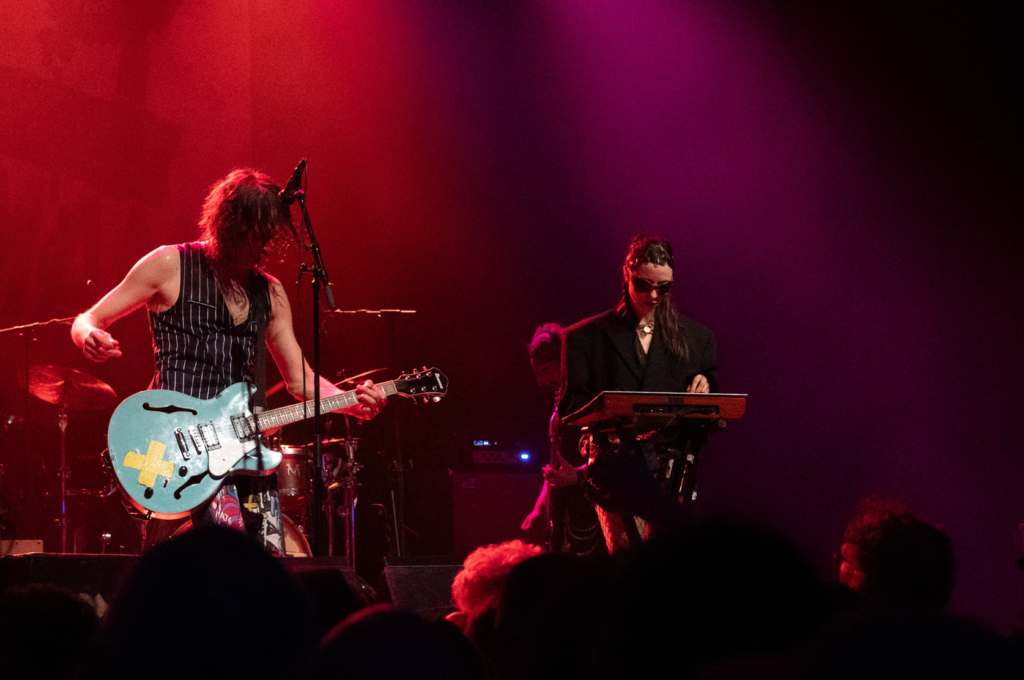 Gogol Bordello performing under red lighting with full band visible
