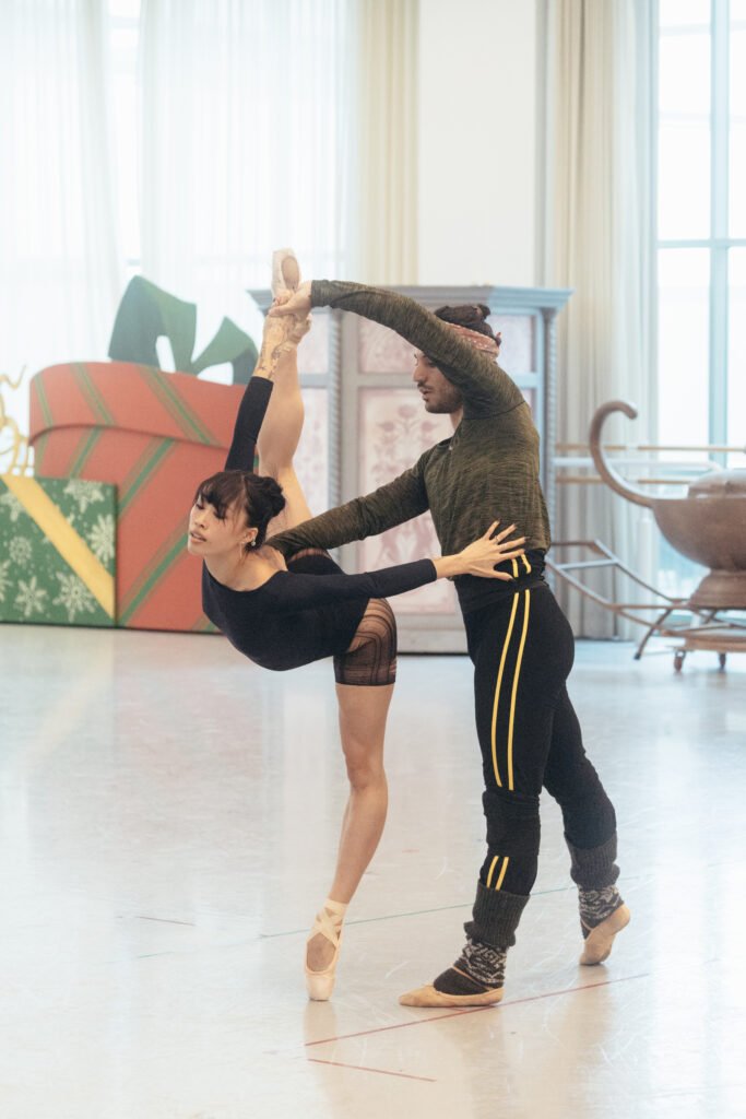 Madeline Woo rehearsing ballet in studio with partner practicing extension and balance