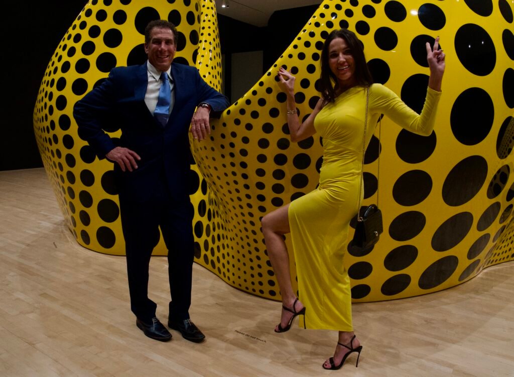 Guests in coordinated yellow outfit posing in front of polka dot art installation at SFMOMA