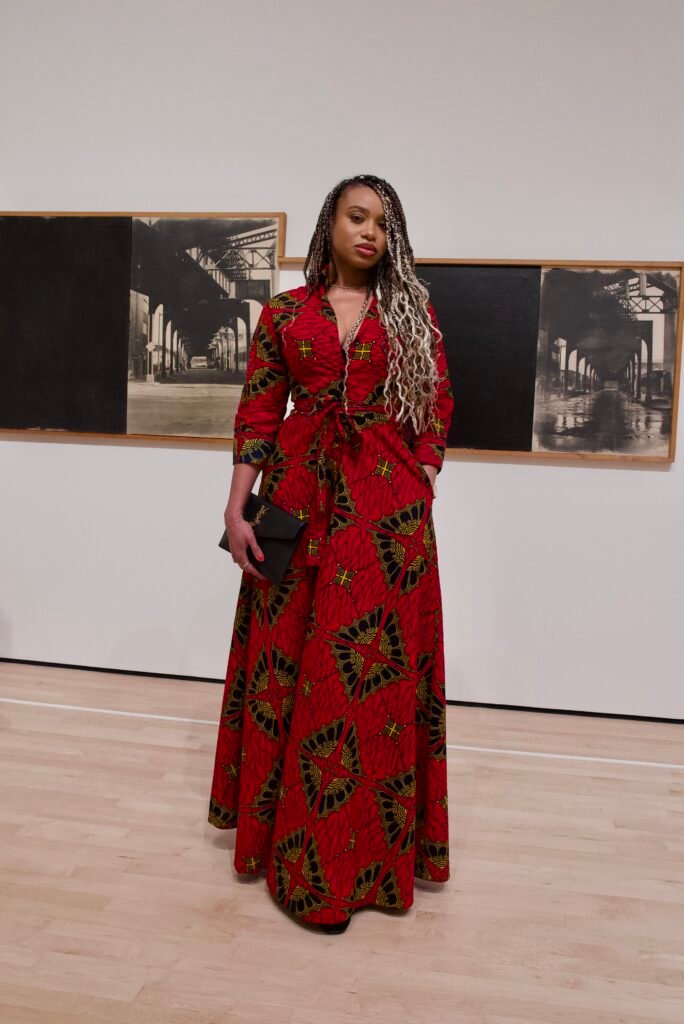 Guest wearing bold red patterned dress standing in front of black and white artwork