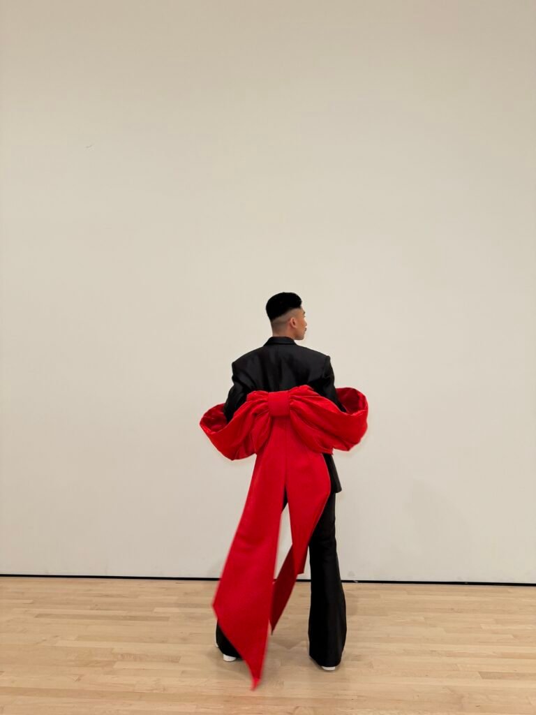 Guest in black suit with oversized red bow detail at SFMOMA Art Bash