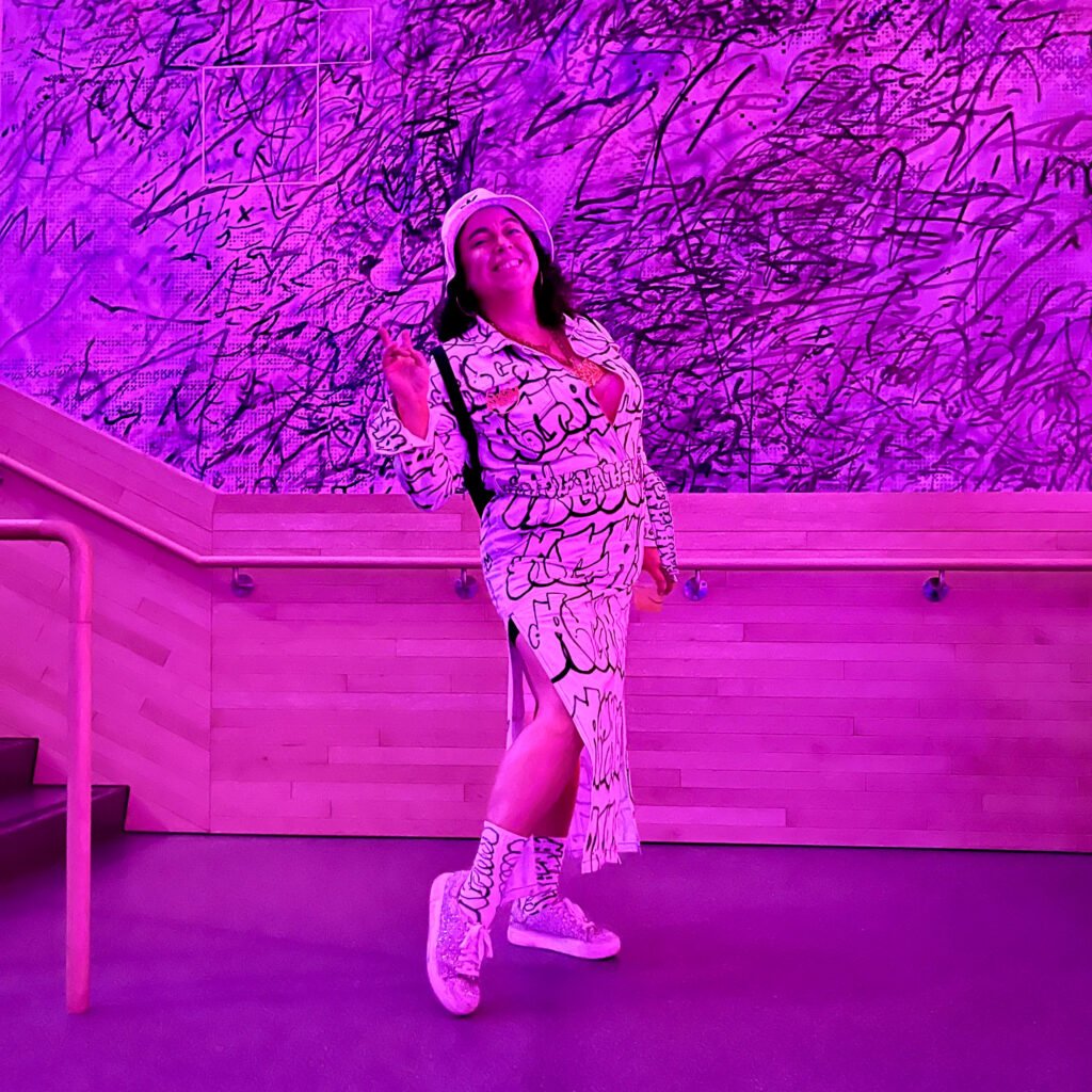 Guest in graffiti-style outfit under pink lighting at SFMOMA Art Bash
