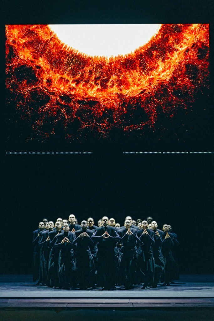 San Francisco Ballet corps standing beneath a fiery LED screen in Mere Mortals