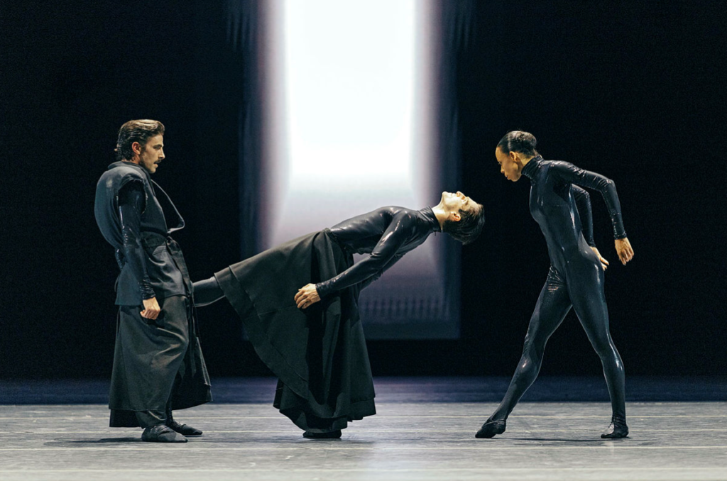 Trio of dancers in sculptural pose under stark lighting in Mere Mortals