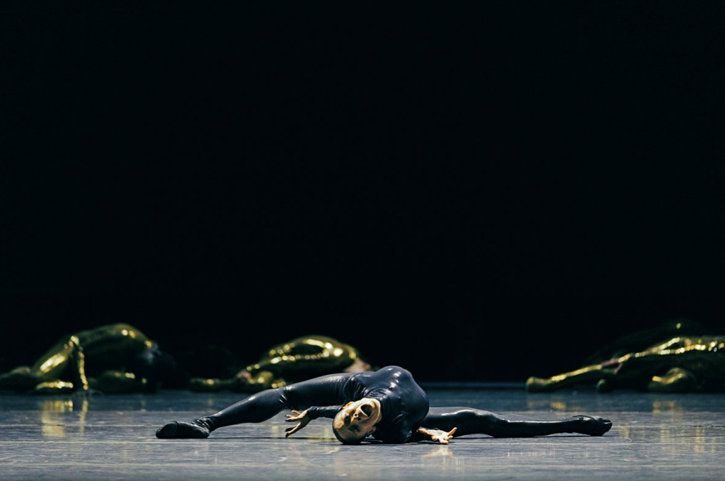 Dancer mid-air leap against dark stage in Mere Mortals