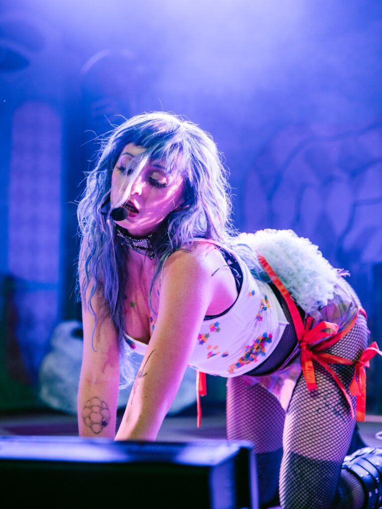 Ashnikko crouched low on stage during live performance with dramatic lighting