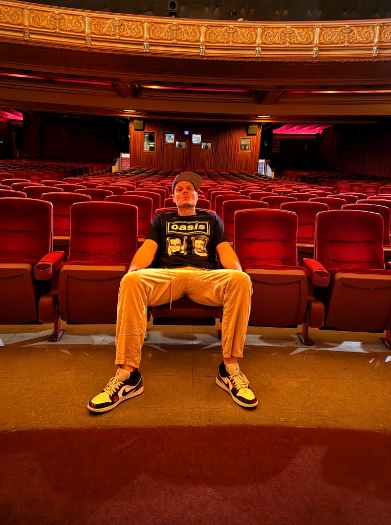Skweezy Jibbs sitting alone inside the historic Grand Lake Theater in Oakland before a screening event
