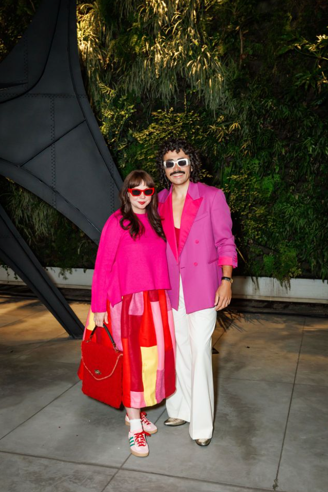 Two guests posing at Art Bash 2026 at SFMOMA in colorful outfits in garden setting