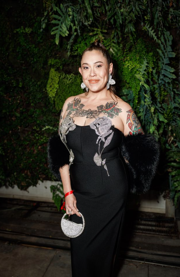 Guest posing at Art Bash 2026 at SFMOMA wearing black gown with tattoos and silver bag