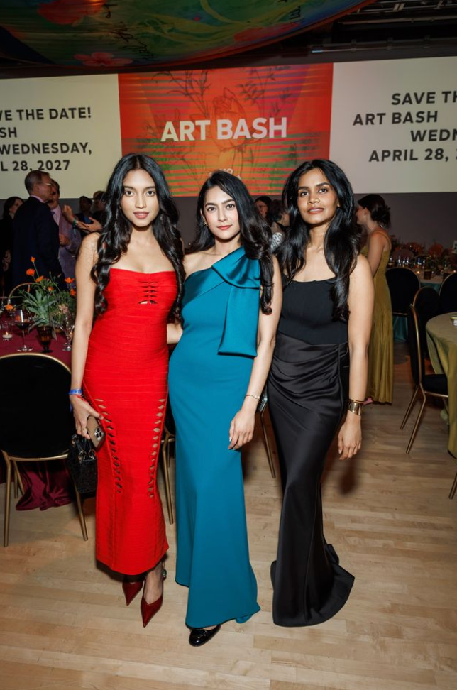 Three guests posing at Art Bash 2026 at SFMOMA in formal dresses with event signage behind