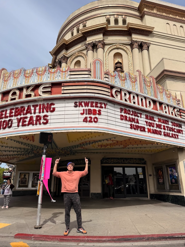 Skweezy Jibbs standing beneath the marquee of the Grand Lake Theater in Oakland