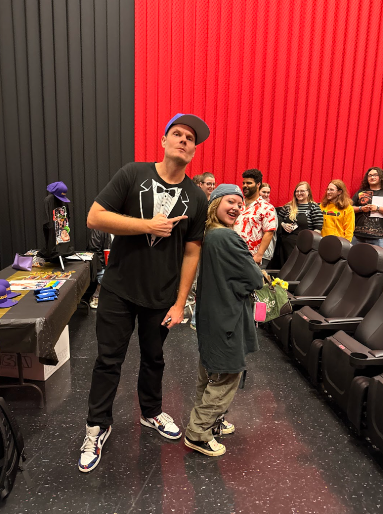 Skweezy Jibbs posing with a young fan inside a movie theater during a meet-and-greet