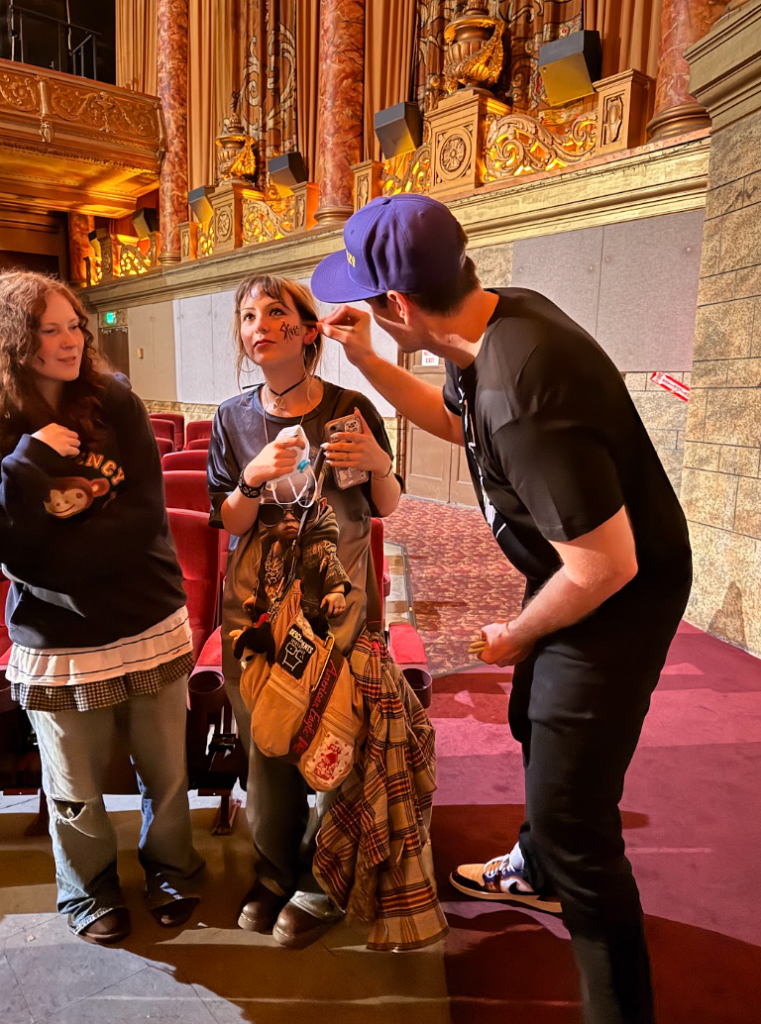 Skweezy Jibbs signing a fan’s face inside a theater during a live event